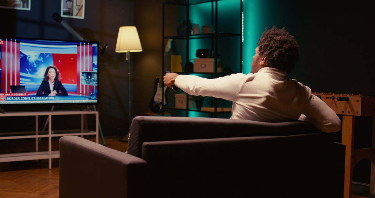 Person relaxing at home watching a news channel on a large modern TV